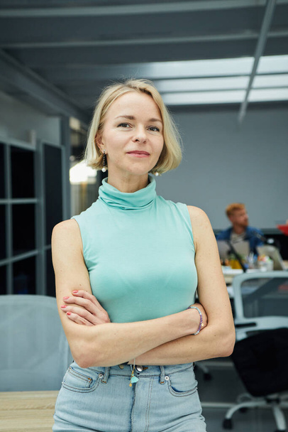Vertical photo of serious confident blonde Caucasian business woman looking at camera standing with arms crossed in office. Executive CEO professional manager posing for business portrait. - Photo, image