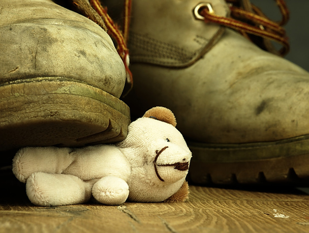 Urso de peluche esmagado por uma bota militar pesada e velha
. - Foto, Imagem