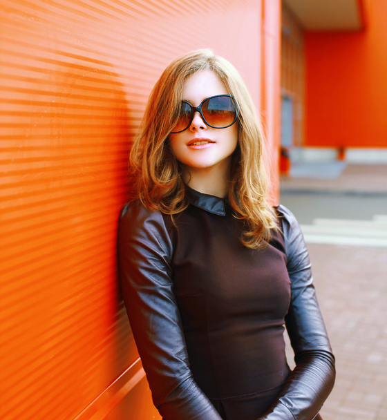 Pretty fashion woman in sunglasses posing against colorful wall  - Photo, image