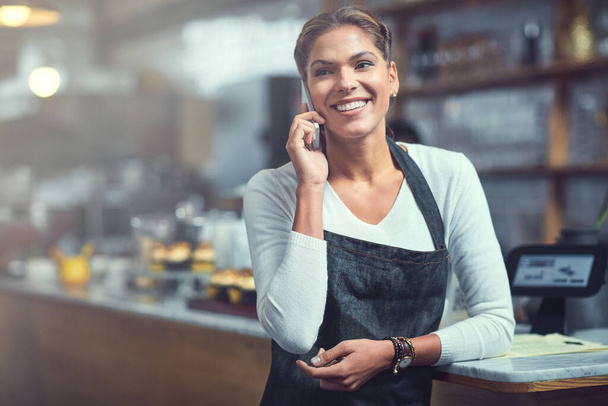 Связаться с клиентами никогда не было так просто. молодая женщина, использующая телефон в магазине, в котором она работает - Фото, изображение