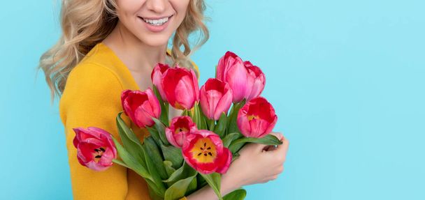 happy young woman with spring tulip flowers on blue background. womens day. - Photo, image