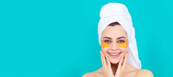 Skin care beauty woman. happy young girl has collagen gold eye patches on face with towel. Beautiful woman isolated face portrait, banner with mock up copy space - Foto, imagen