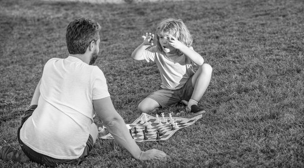 šťastná rodina otce muže a syna dítě hrát šachy na zelené trávě v parku venkovní, vzdělávání. - Fotografie, Obrázek
