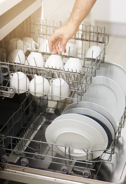 Geschirrspülen muss nie wieder lästig sein. eine Person, die zu Hause eine Geschirrspülmaschine lädt - Foto, Bild