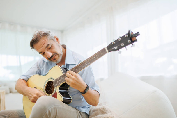 Attractive Mature Adult Man playing acoustic guitar at home. - Photo, Image