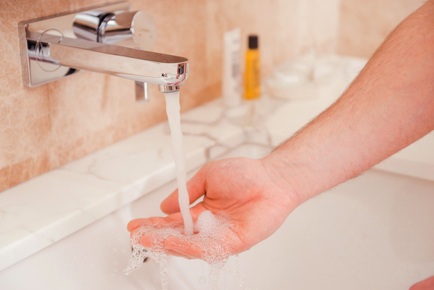 Man washing hands in bathroom - Foto, afbeelding
