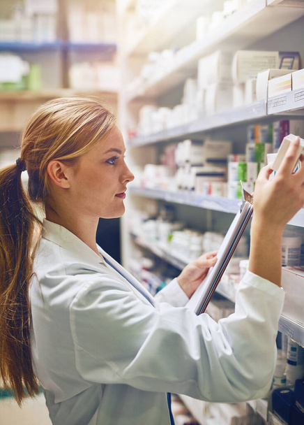 My job is to prevent medication errors. a pharmacist looking at medication on a shelf - Foto, afbeelding