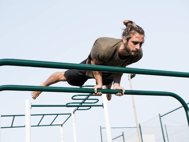 Caucasian man doing elbow lever strength exercise in the calisthenics park - Photo, Image
