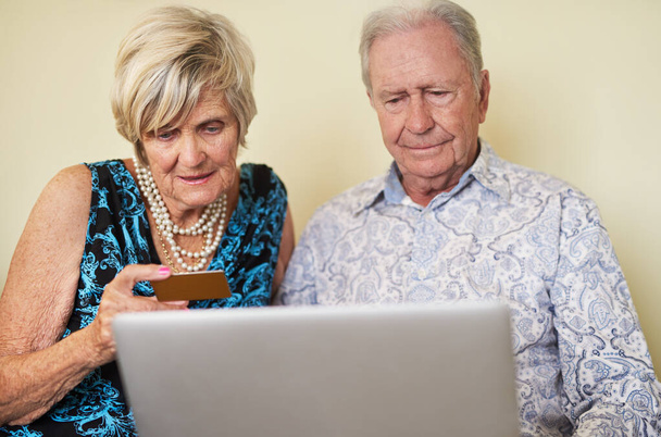 Mantendo sua liberdade financeira com a tecnologia moderna. um casal sênior fazendo um pagamento com cartão de crédito em um laptop juntos em casa - Foto, Imagem