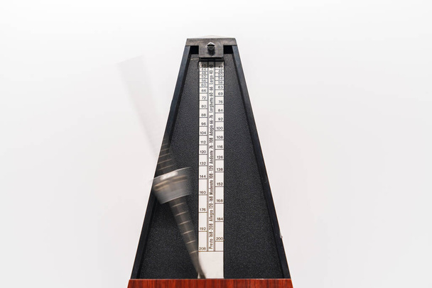 Old fashioned metronome with blurred arm indicating motion isolated on a white background - Foto, Imagem