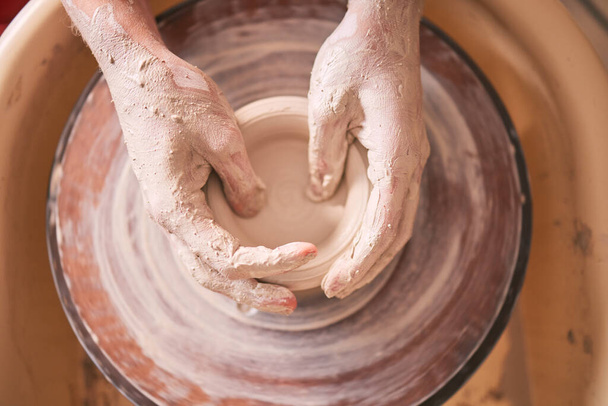 Creative, pottery and design with hands of woman in workshop studio for molding, ceramics and art. Clay, sculpture and manufacturing with girl artisan on wheel for crafting, handmade and hobby. - Foto, afbeelding