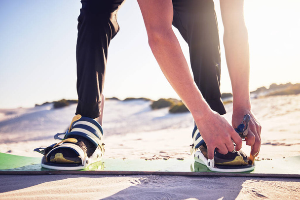 Sand, board and man tie shoes ready for desert surfing, extreme sports and action hobby in nature. Freedom, adventure and feet of athlete outdoors for fitness, exercise and dune surfer training. - 写真・画像