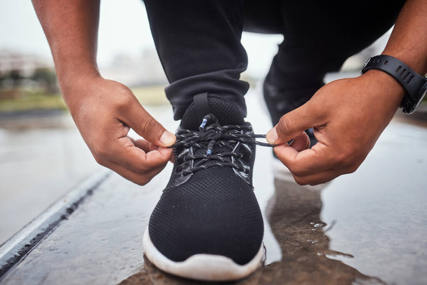 Exercise, shoes and running with a sports man tying his laces for an outdoor cardio or endurance workout. Fitness, footwear and training with a male athlete or runner fastening his shoelaces outside. - Valokuva, kuva
