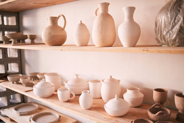 Ceramics, dishes and pottery on shelf in studio, creative store and manufacturing startup. Clay products, background and shelves in workshop, small business and retail craft shop of stock production. - Foto, immagini