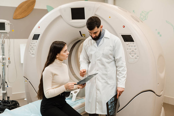 CT Doctor консультує пацієнта і показує мозок рентгенівського випромінювання пацієнту в кімнаті комп'ютерної томографії. Радіолог з КТ сканування показує рентген мозку пацієнту в обчислювальній кімнаті сканування. - Фото, зображення