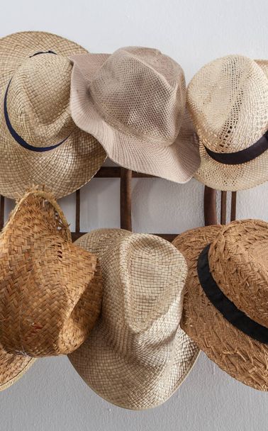 Rack cluttered with hats made from vegetable fibers. Country style - 写真・画像