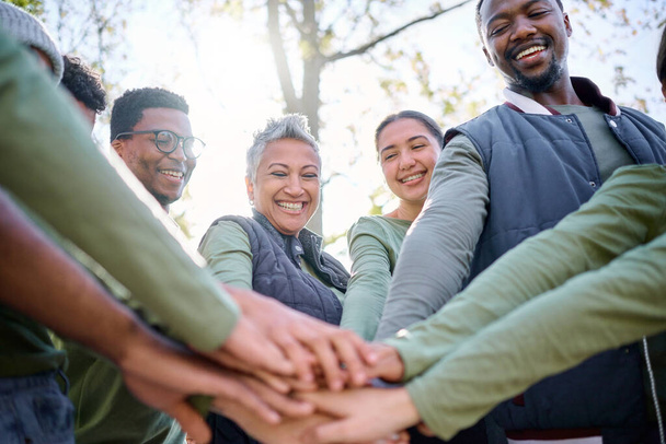 Teamwork, motivation and huddle with senior friends hiking together in the forest or woods from below. Fitness, exercise or nature with a mature man and woman friend group putting hands in a circle. - 写真・画像
