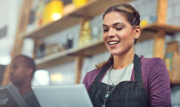 Управляла своим магазином онлайн и в магазине. молодая женщина, пользующаяся цифровой табличкой в магазине, в котором она работает - Фото, изображение