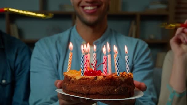 Cropped view African american 30s man hold birthday cake with burning candles two diverse friends blowing party whistles surprising male with festive event congratulate fun celebration make surprise - Filmagem, Vídeo