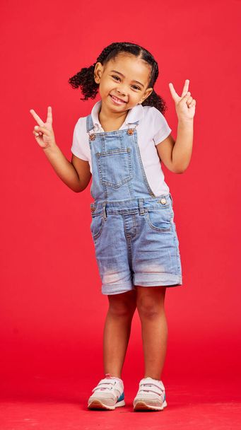Happy, peace sign and smile with portrait of girl for summer, happiness and funny face. Meme, fashion and cute with child and hand gesture for youth, comedy and positive in red background studio. - Fotó, kép