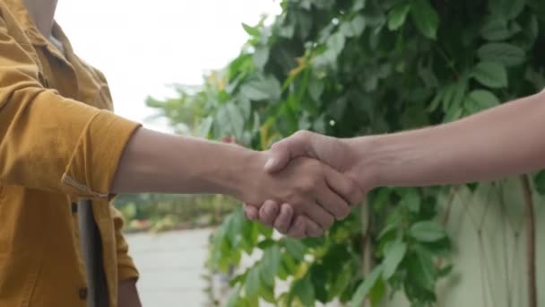 Closeup of two unrecognizable mates shaking hands outdoors when greeting each other - Imágenes, Vídeo