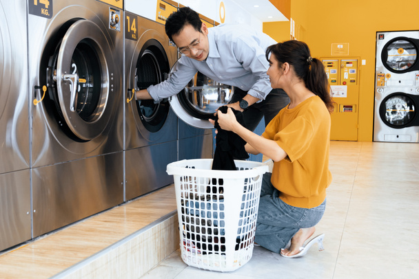 Азиаты используют квалифицированную стиральную машину для стирки одежды в общественных помещениях. Концепция самообслуживания коммерческая прачечная и сушильная машина в общественном помещении. - Фото, изображение