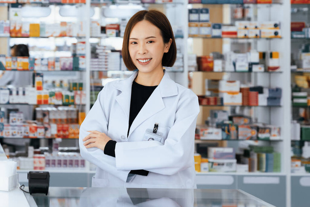 Portrait of young affable pharmacist and qualified pharmaceutical, medicine pill container or bottle mockup for copyspace at pharmacy. Druggist working with her diary job at drugstore, medicine shelf. - Foto, Imagen