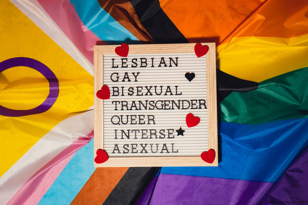 LGBTQIA description frame on Rainbow LGBTQIA flag made from silk material. LESBIAN, GAY, BISEXUAL, TRANSGENDER, QUEER, INTERSEX, ASEXUAL. Symbol of LGBTQ pride month. Equal rights. Peace and freedom - Φωτογραφία, εικόνα