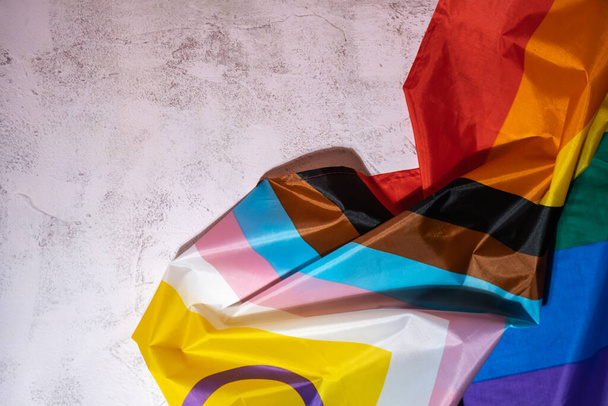 Rainbow LGBTQIA flag made from silk material on concrete background with copy space for your text. Valentines Day greeting card. Symbol of LGBTQ pride month. Equal rights. Peace and freedom. Support - Фото, изображение