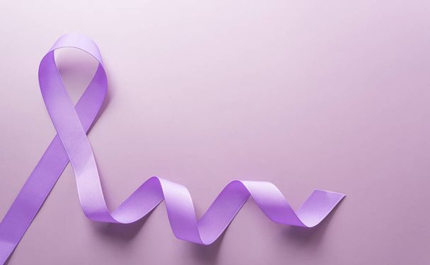 Фиолетовая лента на бумажном фоне для поддержки кампании по случаю Всемирного дня борьбы с раком 4 февраля. - Фото, изображение