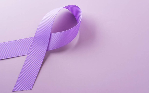 Фиолетовая лента на бумажном фоне для поддержки кампании по случаю Всемирного дня борьбы с раком 4 февраля. - Фото, изображение