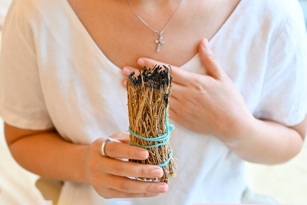 Woman performing ritual of sage burning to cleanse space from negative energy. Self care, physical, mental, emotional, soul. Mindfulness living, spiritual routine. - Φωτογραφία, εικόνα