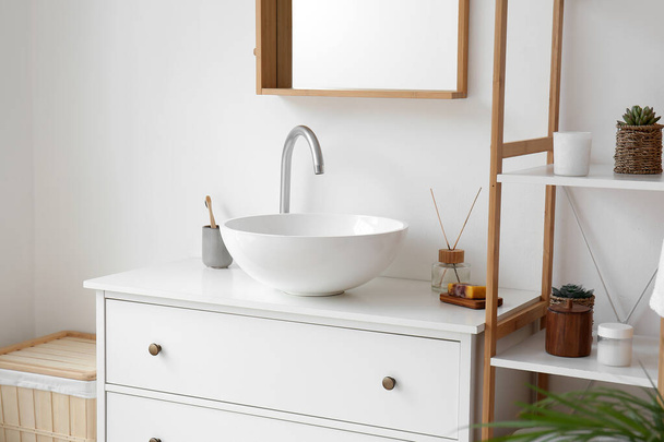 Ceramic sink and bath accessories on drawers in light bathroom - 写真・画像