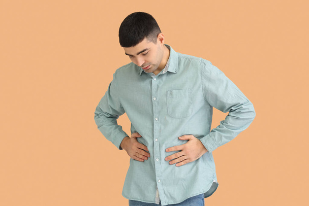 Young man with appendicitis on beige background - Фото, изображение
