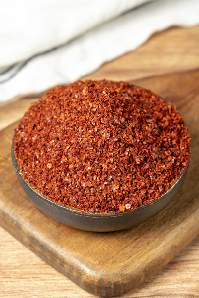 Red pepper flakes. Crushed chili pepper in bowl, dried chili flakes on wooden background. Close up - Foto, imagen