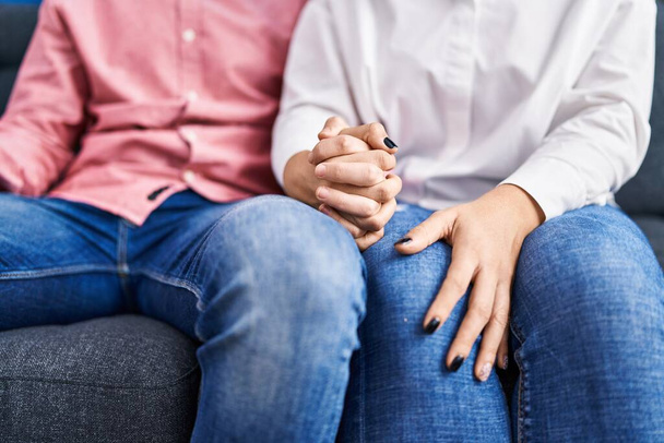 Man and woman couple sitting on sofa with hands together at home - Foto, Imagen