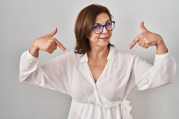 Middle age hispanic woman standing over isolated background looking confident with smile on face, pointing oneself with fingers proud and happy.  - Photo, Image