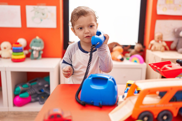 Adorable caucasian boy playing telephone toy standing at kindergarten - Photo, Image