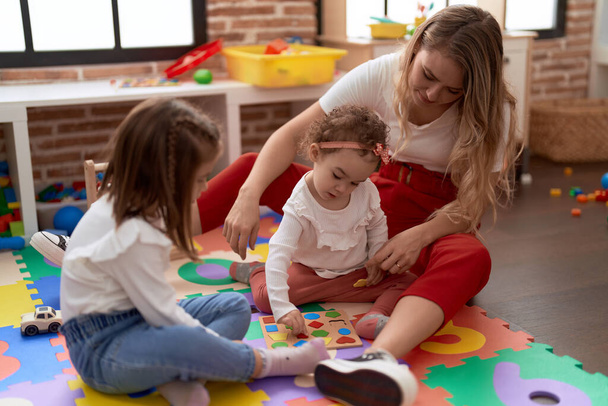Teacher with girls playing with maths puzzle game and construction blocks at kindergarten - Foto, Imagem