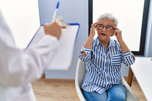 Senior grey-haired woman patient having medical consultation at clinic - Fotó, kép