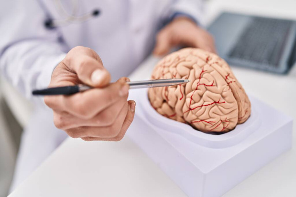 Young man neurologist pointing to brain working at clinic - Zdjęcie, obraz