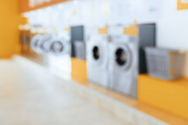 Antecedentes borrosos de lavadoras de monedas calificadas en una tienda pública. Concepto de una máquina de secado y lavandería comercial de autoservicio en una sala pública. - Foto, imagen