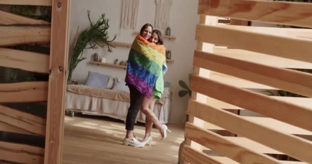 Lgbt women couple rest at home. Embrace and holding each other with pride rainbow flag. Romance and portrait of lesbian couple enjoying. LGBT rights, Lesbian family. Lifestyle and relationships. - Filmati, video