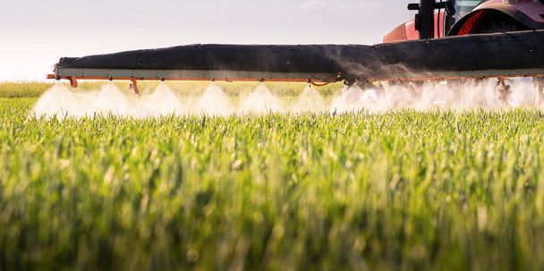 Trattore a spruzzo pesticidi su un campo verde - Foto, immagini