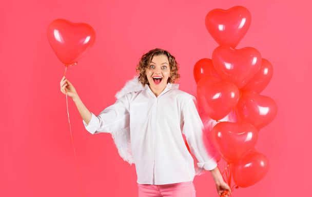 Happy Valentine Day. Curly blonde woman in angel wihgs with red heart shaped balloons. Female cupid - Foto, immagini