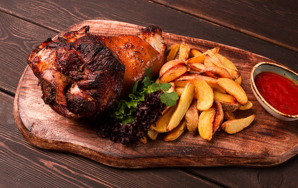 Pork knuckle, in soy-honey sauce, with fried potatoes, on a wooden chopping board, homemade, no people, - Fotó, kép