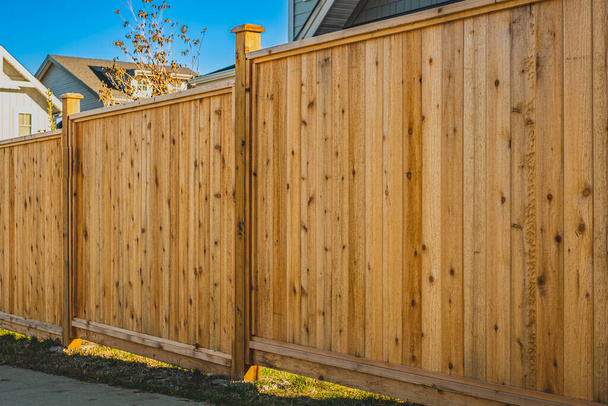 Красивый деревянный забор вокруг дома. Деревянный забор с зеленой лужайкой. Уличное фото, никого, выборочный фокус - Фото, изображение