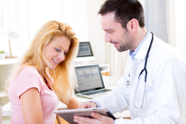 Young doctor showing results on tablet to patient - Photo, image