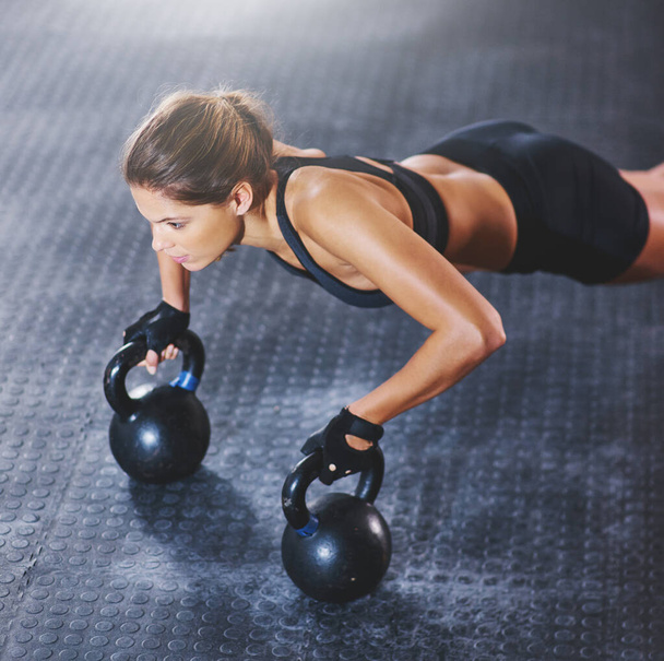 Mindset strong, body even stronger. a young woman working out with kettlebells - Φωτογραφία, εικόνα
