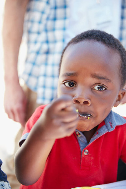 He never wastes his food. Cropped portrait of a young boy getting fed at a food outreach - Valokuva, kuva